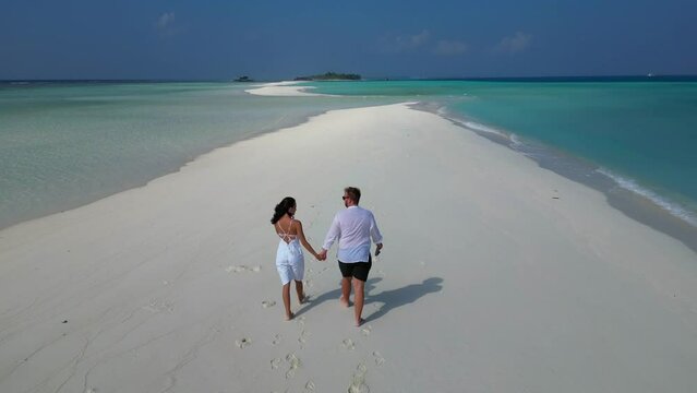 Aerial view of happy couple in love in white clothes spending great time together on Maldives