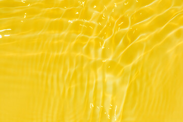 Defocus blurred transparent yellow colored clear calm water surface texture with splashes and...
