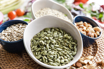 Close-up, a bowl of pumpkin seeds and other healthy foods on the kitchen table.