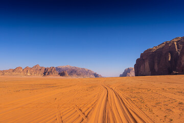 Wadi Rum w Jordanii. Droga na pustynnym piasku między formacjami skalnymi. - obrazy, fototapety, plakaty