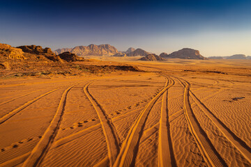 Wadi Rum w Jordanii. Ślady opon samochodowych na pustynnym piasku. - obrazy, fototapety, plakaty
