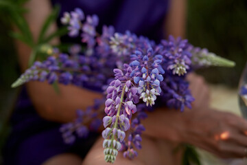 Woman holds purple lupins. Wellness closeness to nature. Self-discovery and connecting with nature concept.