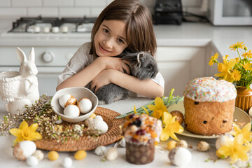 Little girl with a rabbit in the interior of the kitchen, Easter concept.
