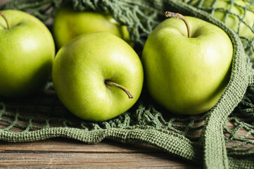 Close-up, green apples in a mesh shopping bag.