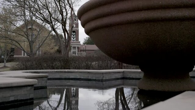 Fountain with still water on the campus of Ole Miss in Oxford, Mississippi with video tilting up.