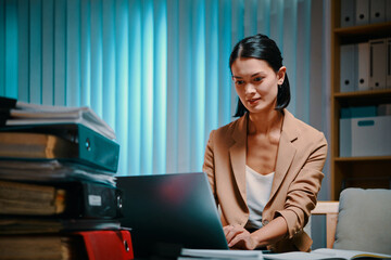 Fototapeta na wymiar Young businesswoman working on laptop in office late at night