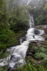 Fototapeta premium Waterfall on a foggy mountain to the river in New Zealand.
