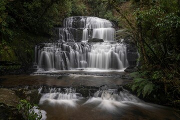 Obraz premium Waterfall on a foggy mountain to the river in New Zealand.