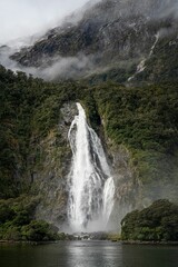 Waterfall on a foggy mountain to the river in New Zealand.