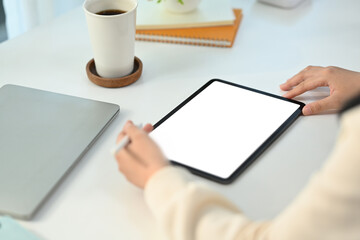 Close up view of young female freelancer working online, browsing internet via digital tablet at working desk