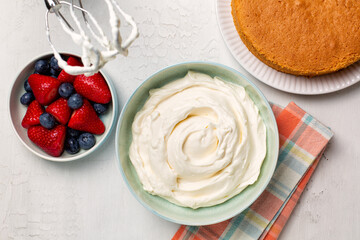 Cooking whipped cream with hand mixer. Vanilla sponge cake, berries, strawberries and blueberries....