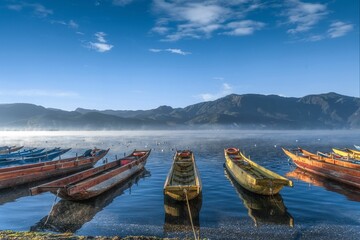 Landscape shot of wooden rowing boats parked on the shore of a beautiful blue lake © Yang6/Wirestock Creators