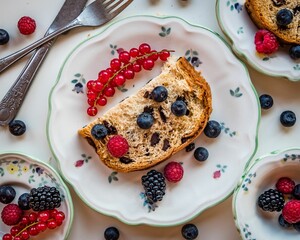 Overhead shot of a slice of bread and colorful berries on a dainty ceramic saucer