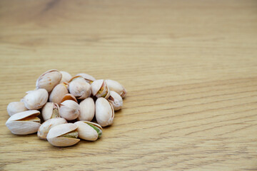 Pistachio nuts on a wooden table. Pistachios background close-up, place for text.