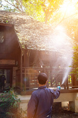 exterminate termite control company employee is using a termite sprayer at customer's house and...
