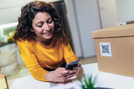 Woman affixing QR codes onto storage boxes. Concept organization, efficiency, or technology in storage management.