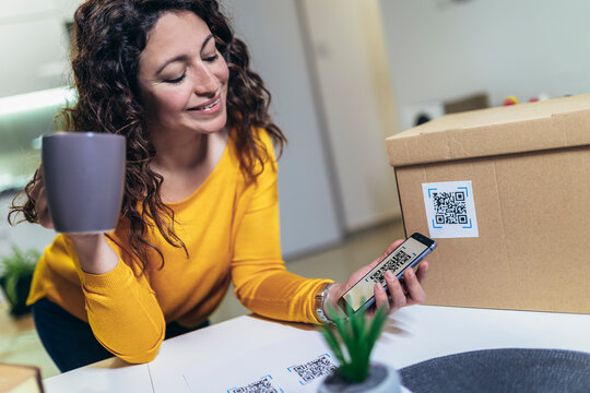Woman affixing QR codes onto storage boxes. Concept organization, efficiency, or technology in storage management.