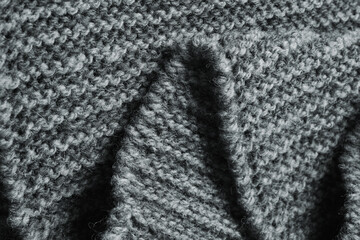 Dark gray zigzag knitted fabric. Knitted texture.