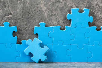 Unfinished blue jigsaw puzzle pieces on grey cement background