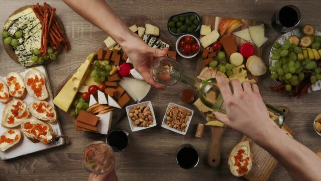 Table with wine appetize and cheese plates, top view. Enjoying dinner with friends. Pouring and drinking white wine.