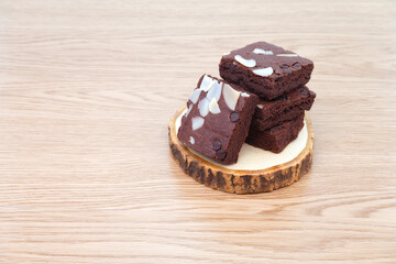 Brownies on wooden tray on wooden background. Chocolate brownie with sliced almond nuts toppings. Chocolate Brownie pieces. selective focus.