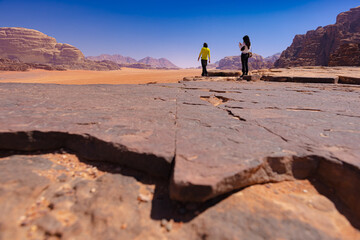 Wadi Rum w Jordanii. Osoby stojące na formacji skalnej patrzące na pustynię i bezchmurne niebo. 