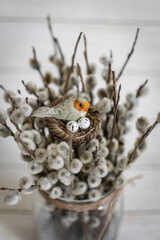 a small bird in a nest on the background of a bouquet of willow in a glass vase, Easter holiday