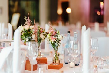 Table decoration with dishes flowers and candles in a bright wedding location