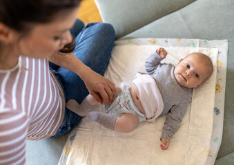 Mother changing diaper to cute baby