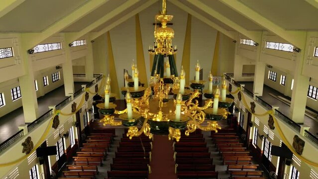Top view inside the catholic church. Large gilded chandeliers overlooking the benches for the parishioners of the Catholic Church. The concept of religion. Camera movement from left to right.