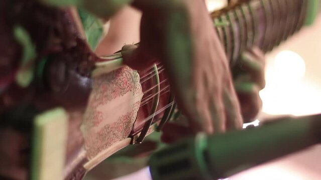 4K Close up of a man playing an Indian Sitar, looking up the neck of the instrument