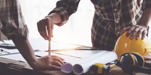 Obraz premium Architect and Engineer working with blueprints for architectural plan, engineer sketching a construction project, green energy concept