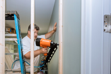 Air hammer is used by builder to nail wooden beams into framework of housing frame in order for building take place