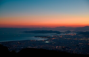 Aerial shot over the cityscape of illuminated Athens at a bright red sunset