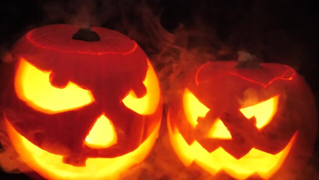 Slow motion of smoke over two illuminated Halloween pumpkins