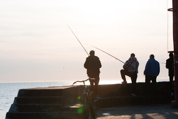 Anglers catch fish in the sea at sunset