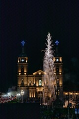 Fototapeta na wymiar Vertical shot of fireworks in front of church during city's holidays of Tuxpan, Jalisco, Mexico