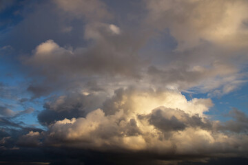 Fototapeta na wymiar Storm cloudy epic dramatic sky with dark rain grey cumulus cloud in yellow sunlight and blue sky background texture, thunderstorm, heaven