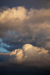 Obraz premium Storm cloudy dramatic sky with dark rain grey cumulus cloud in yellow sunlight and blue sky background texture, thunderstorm, heaven