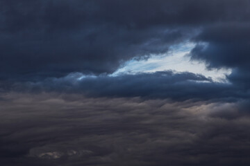 Obraz premium Epic Dramatic storm dark grey cumulus rain clouds against blue sky background texture, thunderstorm