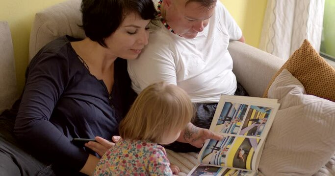 Person with special needs looks at photobook with photos surrounded by relatives at home. LGBT family with kids. 13.09.2022 Litevska, Kladno, Czech Republic