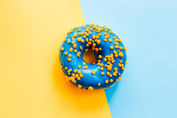 Blue-yellow glaze donut on blue-yellow paper.
