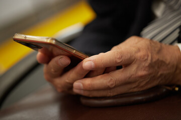通勤電車の中でスマホを操作するシニア男性の手元