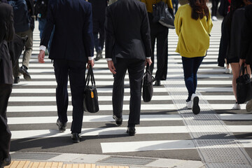 都市の交差点の横断歩道を渡るビジネスマンと人々の姿