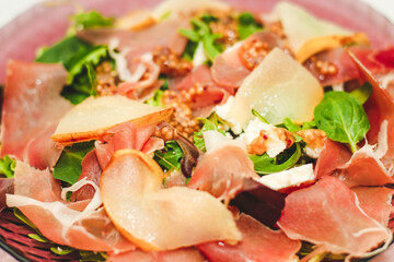 Salad with herbs, arugula, prosciutto, cheese, green olives and nuts.
