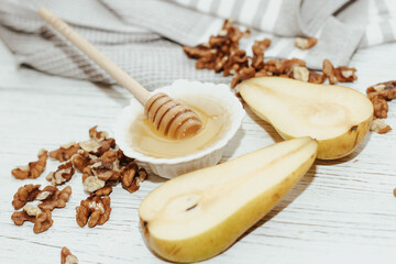 Fototapeta na wymiar Liquid organic honey in white bowl with pears, wooden honey spoon.