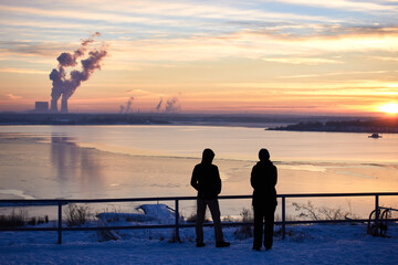 Fototapeta premium View over the frozen Störmthal Lake in winter. colored sky at sunset. reflection of the lippendorf power plant on the ice.