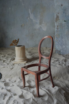 Photo studio in the style of minimalism. With sand, old walls and a chair without a seat. Sadness, time gone