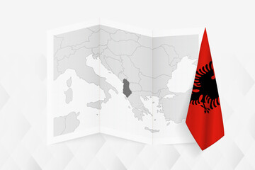 A grayscale map of Albania with a hanging Albanian flag on one side. Vector map for many types of news.