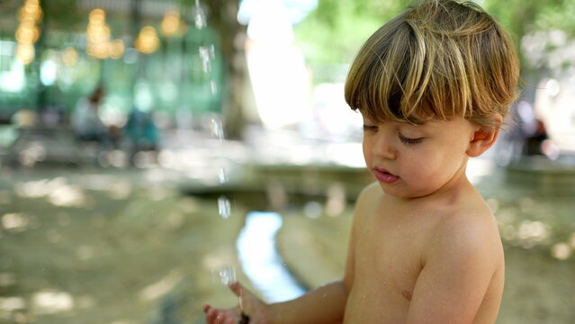 Child washing hands outside during heat day. Refreshing water during summer day. Little boy wearing bathing suit brief